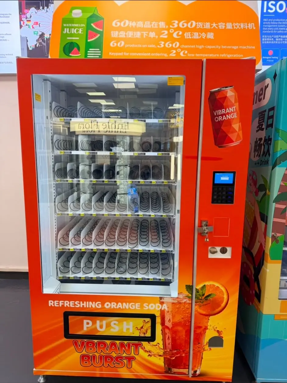 Orange gestalteter Spiralautomat, ganzes Gerät: Glasfront mit sechs Ebenen Spiralfächern, rechts daneben Tastenfeld, Kartenleser und Münzeinwurf.