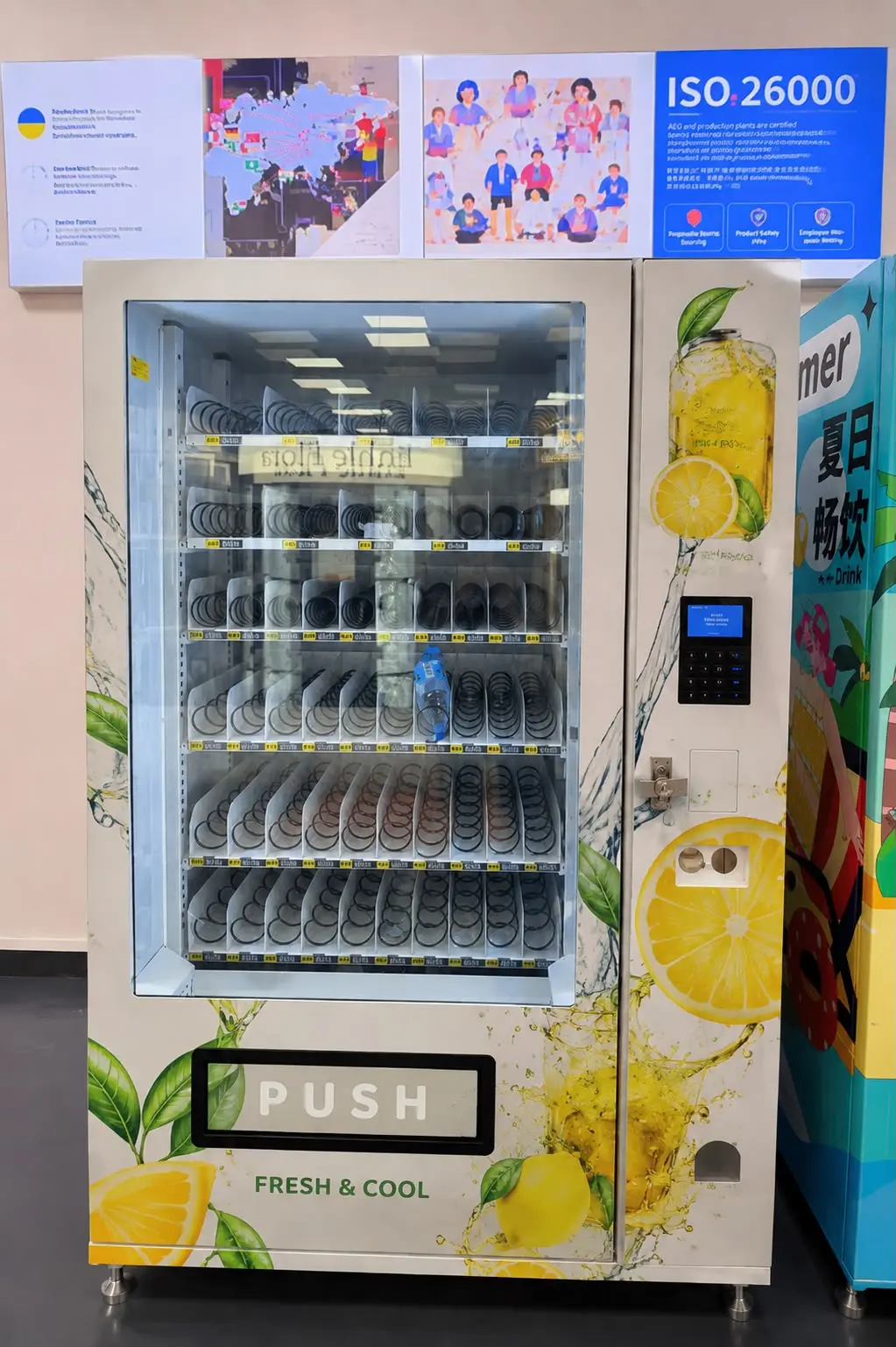 Light-coloured spiral machine with a lemon motif, the whole unit: glass front with six levels of spiral channels, with keypad, card reader and coin slot to the right.