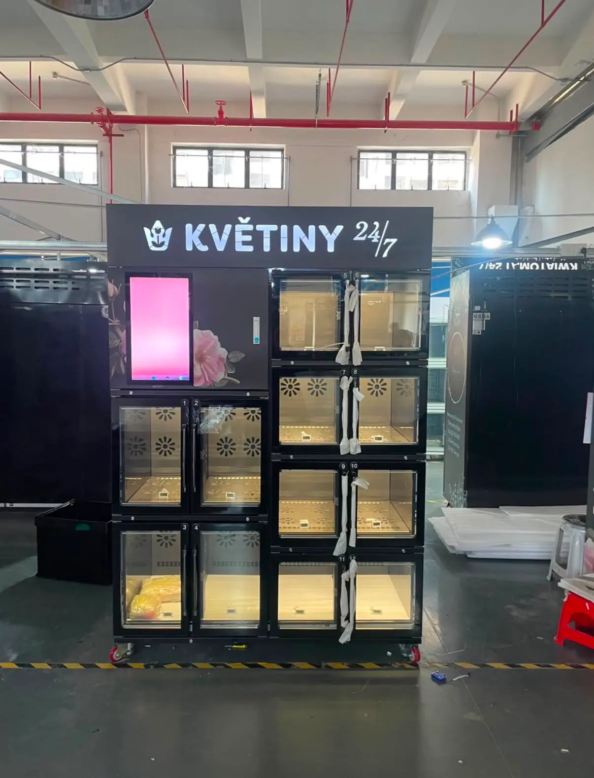 Aufgestellter Zwölffach-Automat in Schwarz, die Leuchtblende trägt die Beschriftung des Kunden.