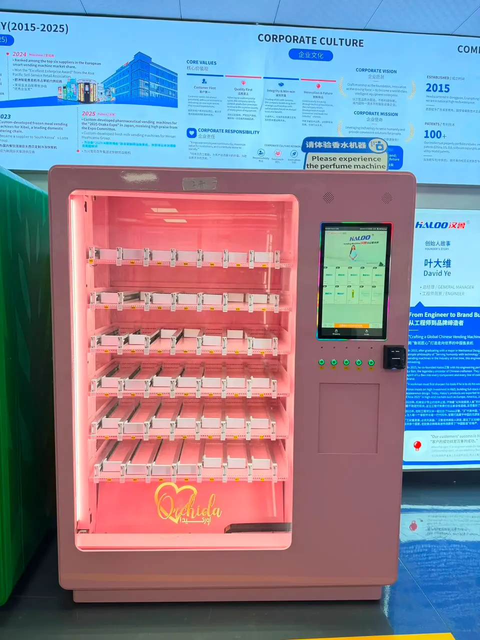 Ein Automat desselben Modells, ganzes Gerät: rosa Gehäuse, sechs Ebenen Gleitkanäle hinter beleuchtetem Glas, daneben Touchscreen und Kartenleser. Die Bahnen sind noch leer.